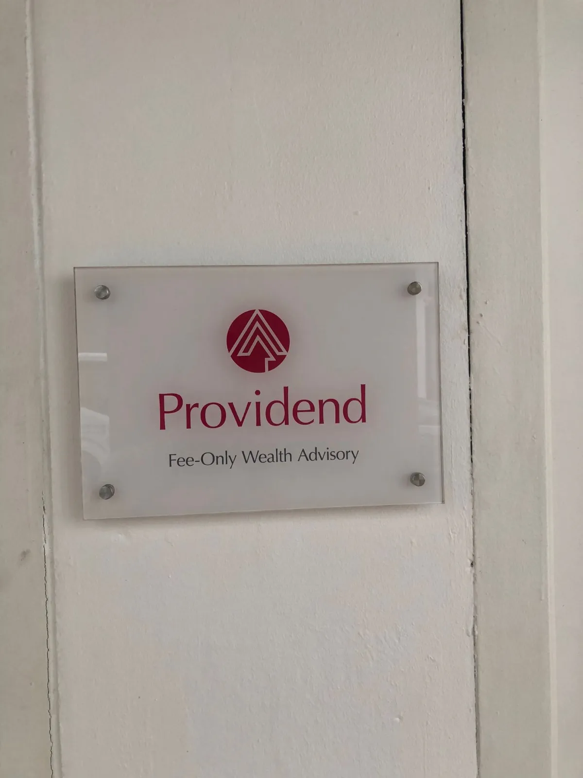 Frosted acrylic nameplate with printed company logo mounted on a wall with four stainless-steel stand-offs